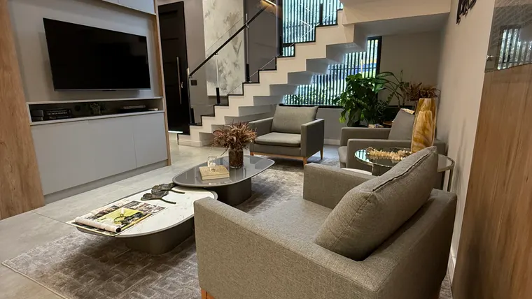 Sala de estar da Vallorize com sofás, TV e escada ao fundo
