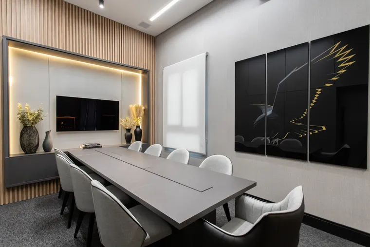 Sala de reuniões da Vallorize com mesa para oito lugares, TV e painel da águia dourada